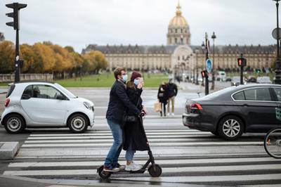 A masked couple ride an electric scooter by the Invalides memorial, in Paris. AP Photo