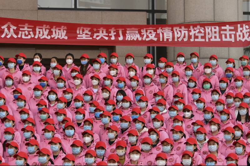 Medical workers gather near a banner that reads 'Unite as one, resolutely win the battle against epidemic' during a departure ceremony before leaving for Shanghai, in Jinan, east China's Shandong Province. AP