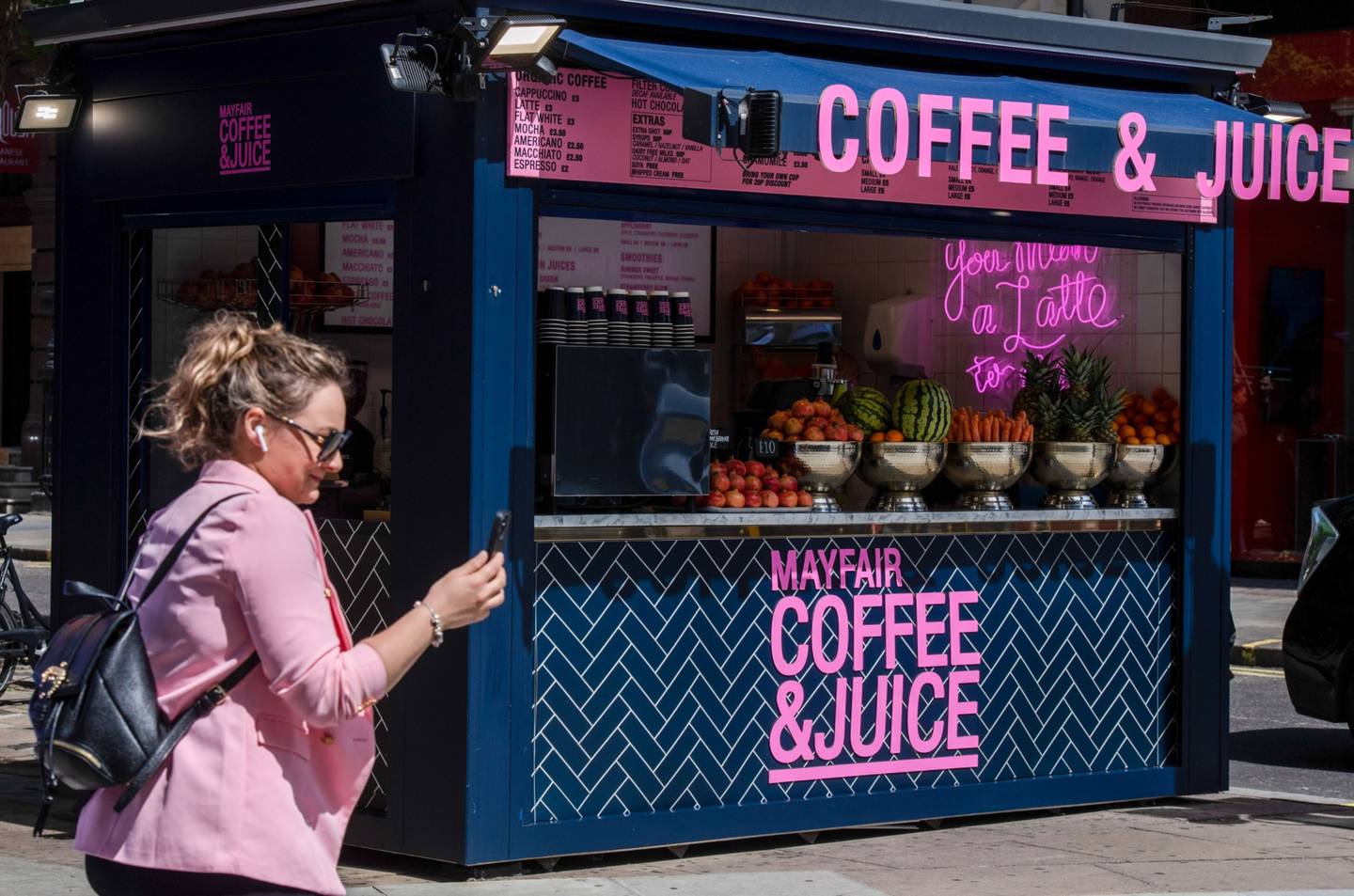 A pedestrian passes a coffee and juice stall on Oxford Street in London. Bloomberg