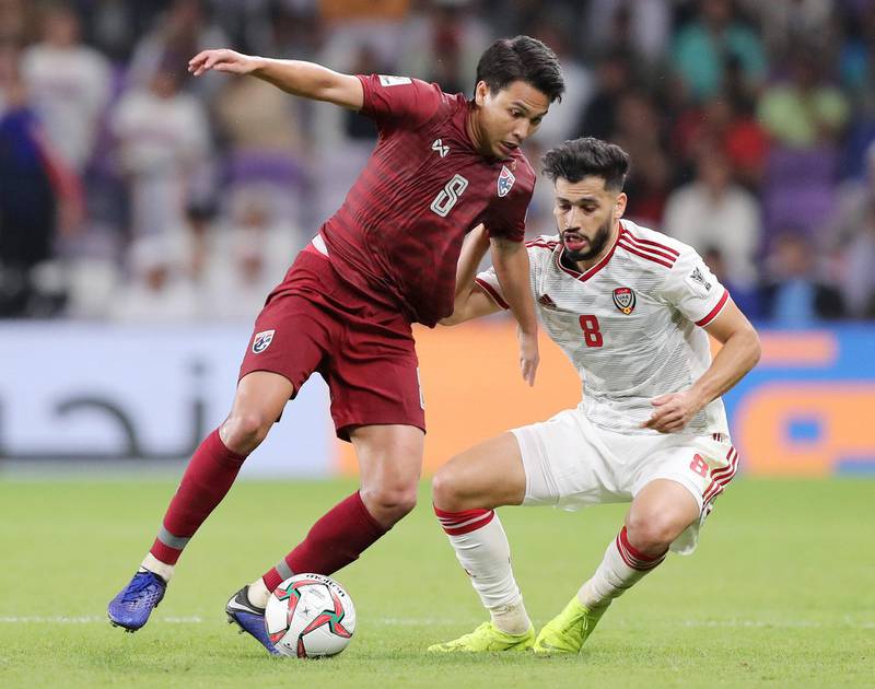 Al Ain, United Arab Emirates - January 14, 2019: Majed Hassan Ahmad of UAE and Thitiphan Puangjan of Thailand battle during the game between UAE and Thailand in the Asian Cup 2019. Monday, January 14th, 2019 at Hazza Bin Zayed Stadium, Al Ain. Chris Whiteoak/The National