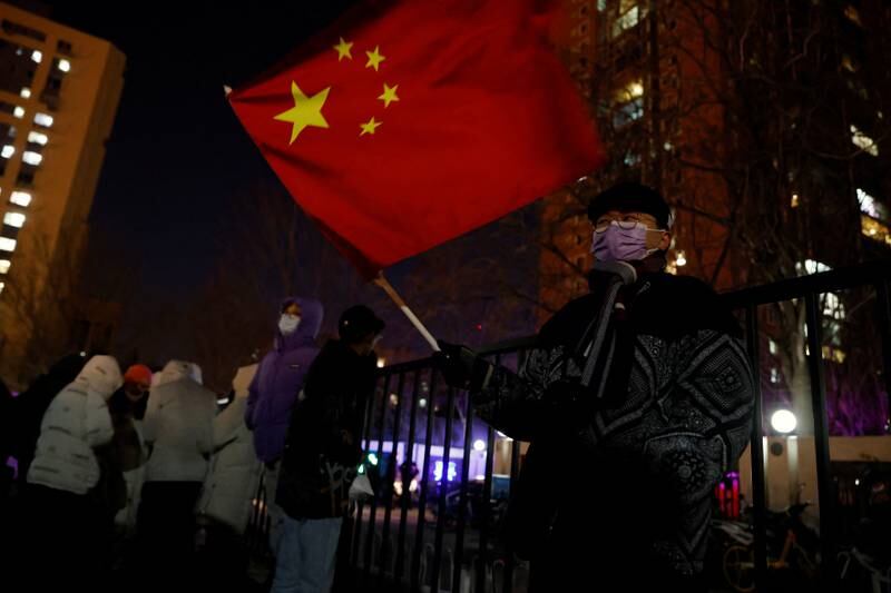 A man waves a Chinese flag as people gather near the National Stadium, also known as the Bird's Nest, for the opening ceremony of the Beijing 2022 Winter Olympics, in Beijing, China. Reuters