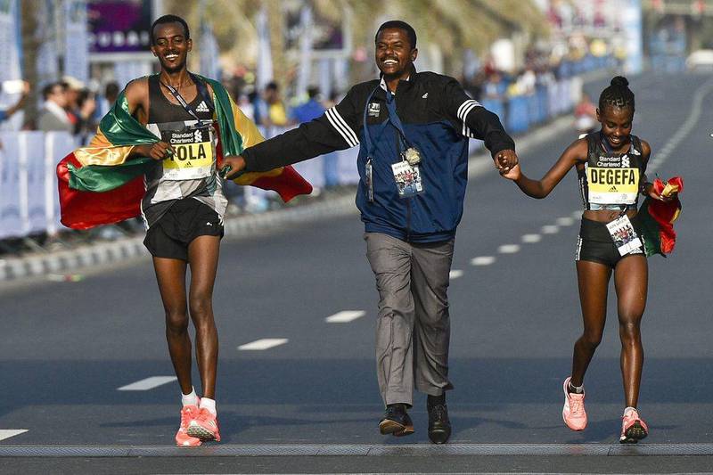 Ethiopian runners Worknesh Degefa, right, and Tamirat Tola, left, celebrate after winning the Dubai marathon on January 20, 2017. Middle-distance legend Kenenisa Bekele, who was aiming to add the marathon world record to his 5,000 metres and 10,000 metres records, limped out of the Dubai event after a fall. AFP / STRINGER

