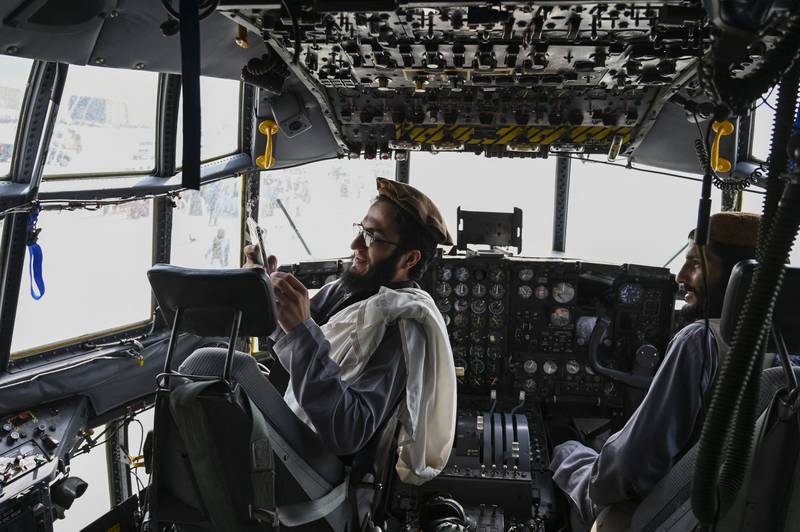 Taliban fighters sit in the cockpit of an Afghan Air Force aircraft at the airport in Kabul on August 31, 2021. AFP