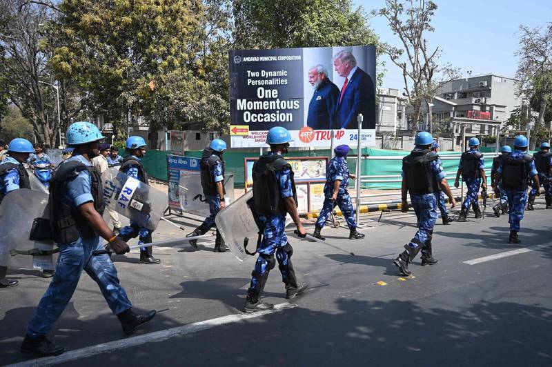 Rapid action force (RAF) personnel patrol along a street past a billborad displaying pictures of India's Prime Minister Narendra Modi and US President Donald Trump in Ahmedabad, ahead of Trump's arrival.  AFP