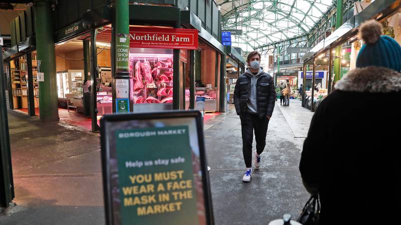 People wearing face masks walk along the normally busy Borough Market in south London. AP Photo