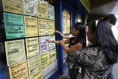 Filipino applicants look at job offers displayed on a glass window of a recruitment agency in Manila. Cheryl Ravelo / Reuters
