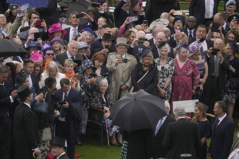 Guests brave the rain at the first garden party of the season at Buckingham Palace. AP