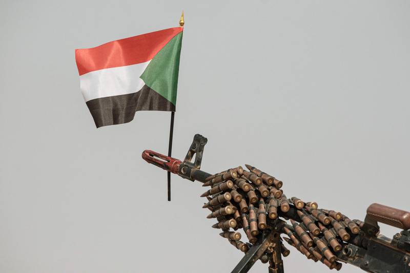 A Sudanese flag placed above the muzzle of a machine gun covered with an ammunition belt of the Rapid Support Forces (RSF) paramilitaries before a rally for supporters of Sudan's ruling Transitional Military Council (TMC) in the village of Abraq, about 60km northwest of Khartoum.  AFP