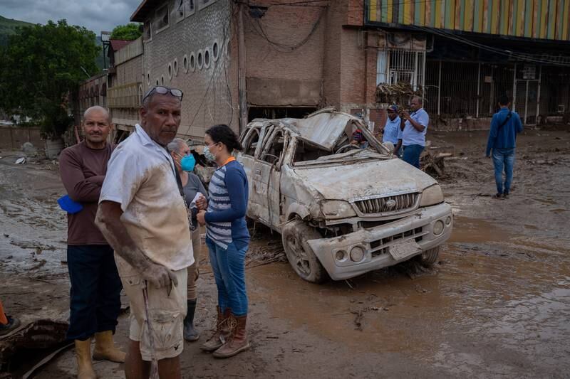 People look at a vehicle destroyed by the overflow of the Los Patos river in Tejerias, Aragua state, Venezuela, 09 October 2022.   EPA/Rayner Pena R. 