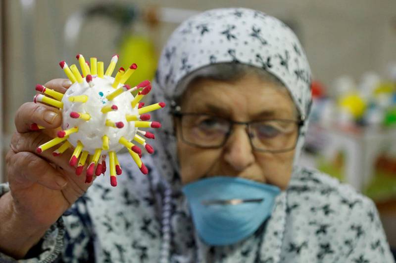 An elderly Palestinian woman displays a model of a microscopic view of coronavirus in a nursing home that stepped up preventive measures to protect patients amid concerns about the spread of the disease, in Jenin, in the Israeli-occupied West Bank, on April 2, 2020. Reuters