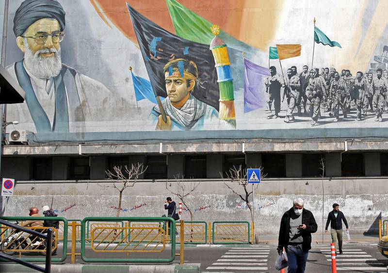 An Iranian man wearing a mask walks under a mural bearing an image of Iran's Supreme Leader Ayatollah Ali Khamenei in Tehran on March 4, 2020. Iran has scrambled to halt the rapid spread of the COVID-19 virus, shutting schools and universities, suspending major cultural and sporting events, and cutting back on work hours.
 / AFP / ATTA KENARE
