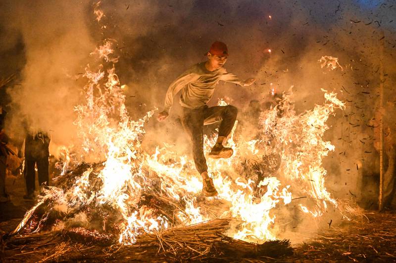 This photo taken on February 28, 2023 shows a man jumping over a bonfire in order to get rid of bad luck in Jieyang, in China's southern Guangdong province.  (Photo by AFP)  /  China OUT