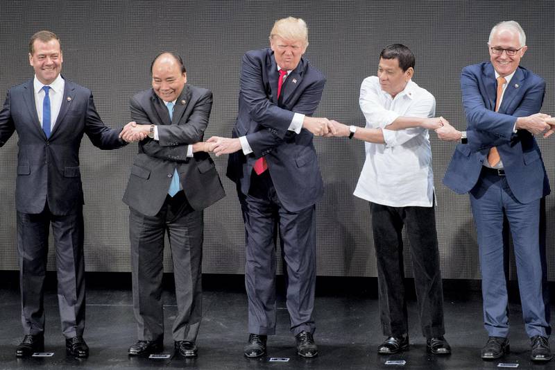 (L-R) Russian Prime Minister Dmitri Medvedev, Vietnam's Prime Minister Nguyen Xuan Phuc, US President Donald Trump, Philippine President Rodrigo Duterte and Australia Prime Minister Malcolm Turnbull join hands for a family photo during the opening ceremony of the 31st Association of South East Asian Nations (ASEAN) Summit in Manila on November 13, 2017. - World leaders are in the Philippines' capital for two days of summits. (Photo by JIM WATSON / AFP)