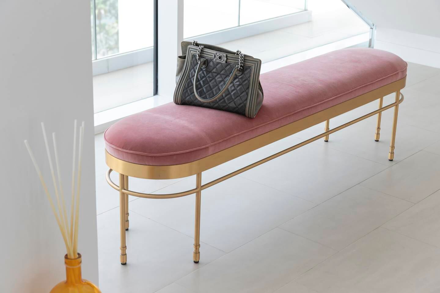 A bench at the entrance has simple gold legs and pink velvet upholstery. Antonie Robertson / The National
