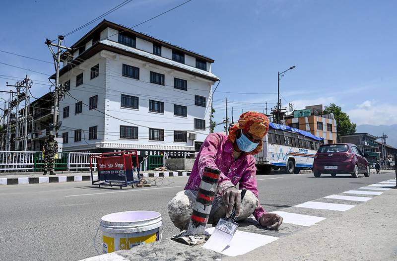 A migrant labourer paints white road markings on the International Labour Day in Srinagar. AFP
