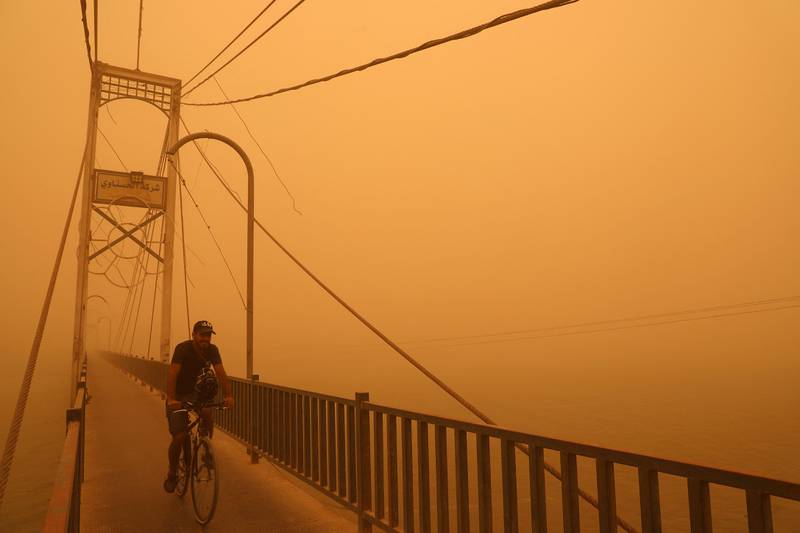 Cycling along a pedestrian bridge amid a Nasiriyah dust storm. AFP