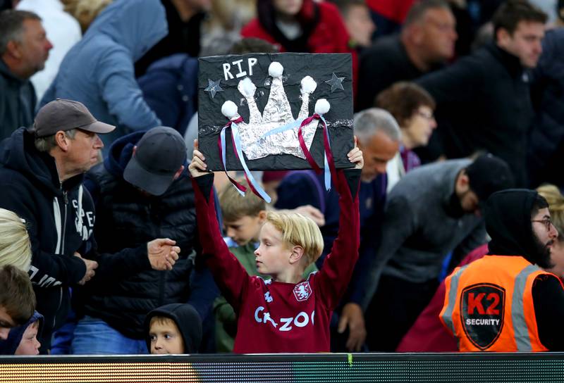 An Aston Villa fan holds up a sign paying tribute to Queen Elizabeth II at Villa Park. PA