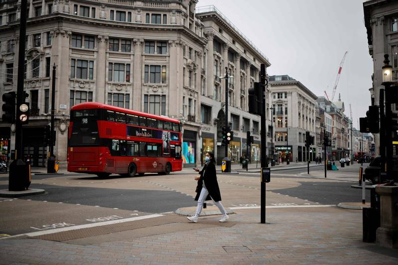 A woman wearing a face mask crosses Oxford Circus in central London on January 8, 2021, as England entered a third lockdown due to the novel coronavirus Covid-19. Faced by a sharp rise in coronavirus infections, driven by the new strain, England entered a strict lockdown on January 5, 2021, with schools and non-essential shops closed for at least six weeks after previous measures failed to halt the steep rise in cases. / AFP / Tolga Akmen
