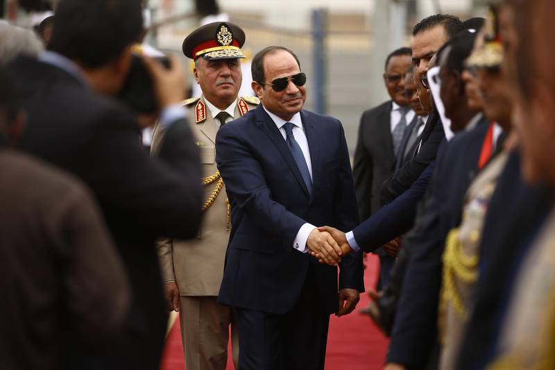 Egyptian President Abdel-Fattah al-Sisi (C) shakes hands with Sudanese officials as he is received by his Sudanese counterpart at Khartoum International Airport outside the Sudanese capital on October 25, 2018.  / AFP / ASHRAF SHAZLY
