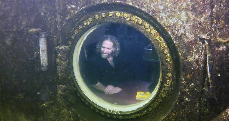 Joseph Dituri peers out of a large porthole in Jules's Undersea Lodge. AP