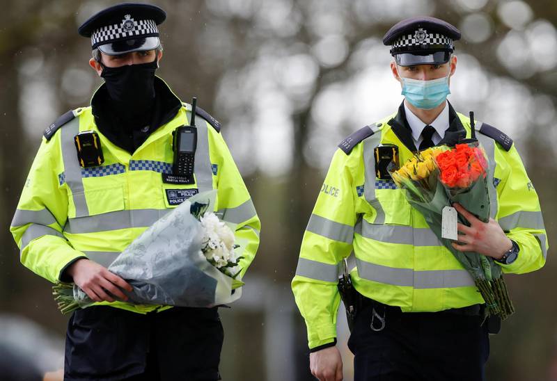 Police officers bring flowers at the golf course entrance, as the investigation into the disappearance of Sarah Everard continues, in Ashford, Britain, March 11, 2021. REUTERS/Paul Childs