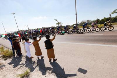 Emirati boys wave the national flag as the pack ride during the seventh stage. AFP