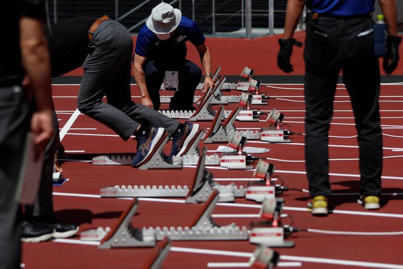 Officials check on starting blocks before the start of the morning session of the athletics test event. Reuters