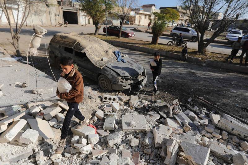 Residents walk over the rubble of a building destroyed by a rocket in the town of Azaz, Aleppo province. AFP