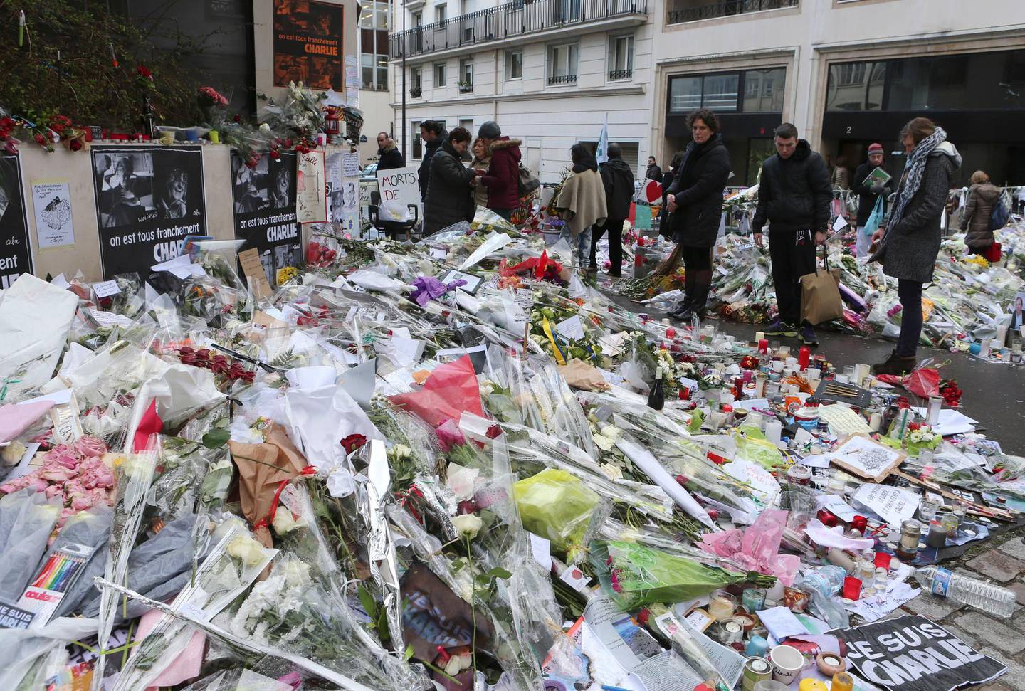 FILE - In this Jan. 14, 2015 file photo, flowers lay outside Charlie Hebdo headquarters in Paris. The January 2015 attacks against Charlie Hebdo and, two days later, a kosher supermarket, touched off a wave of killings claimed by the Islamic State group across Europe. Seventeen people died along with the three attackers. Thirteen men and a woman accused of providing the attackers with weapons and logistics go on trial on terrorism charges Wednesday Sept. 2, 2020. (AP Photo/Jacques Brinon, File)