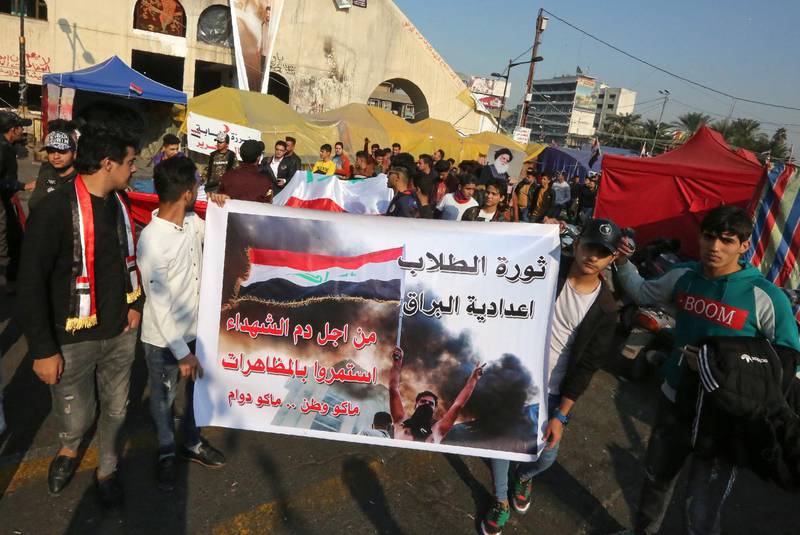 Iraqi anti-government protesters carry a banner as they rally during ongoing demonstrations in the capital Baghdad's Tahrir square. AFP