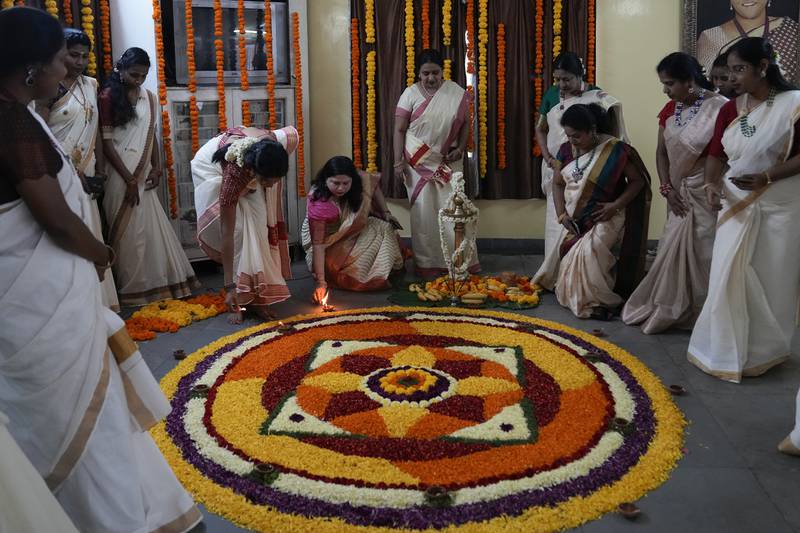 Women light lamps around a floral pookalam motif during festivities marking Onam in Hyderabad. AP