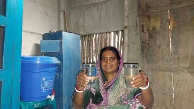 A woman shows the quality of water after a biosand filter has removed contaminants from the water