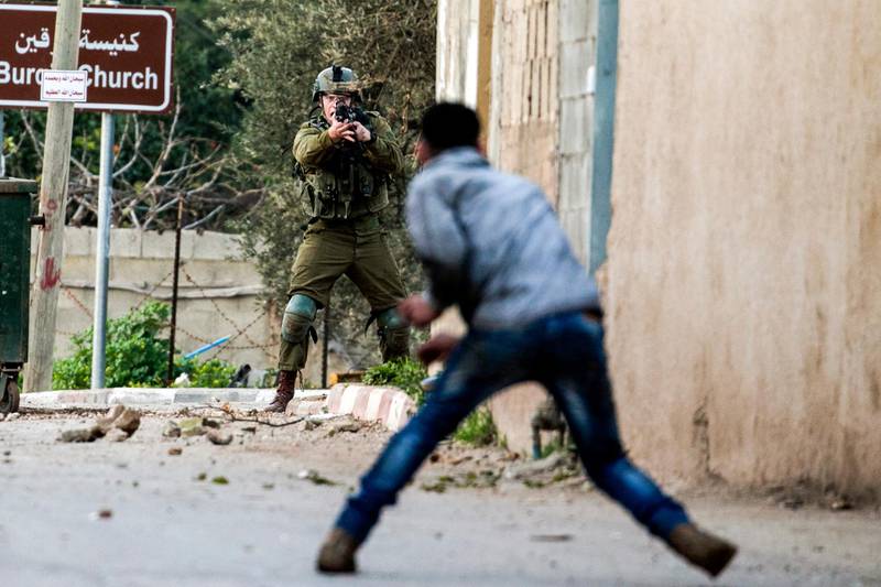 TOPSHOT - A Palestinian protester confronts an Israeli soldier during an army search operation in the Palestinian village of Burqa, about 18 kilometres northwest of Nablus in the occupied West Bank, on February 3, 2018. / AFP PHOTO / JAAFAR ASHTIYEH