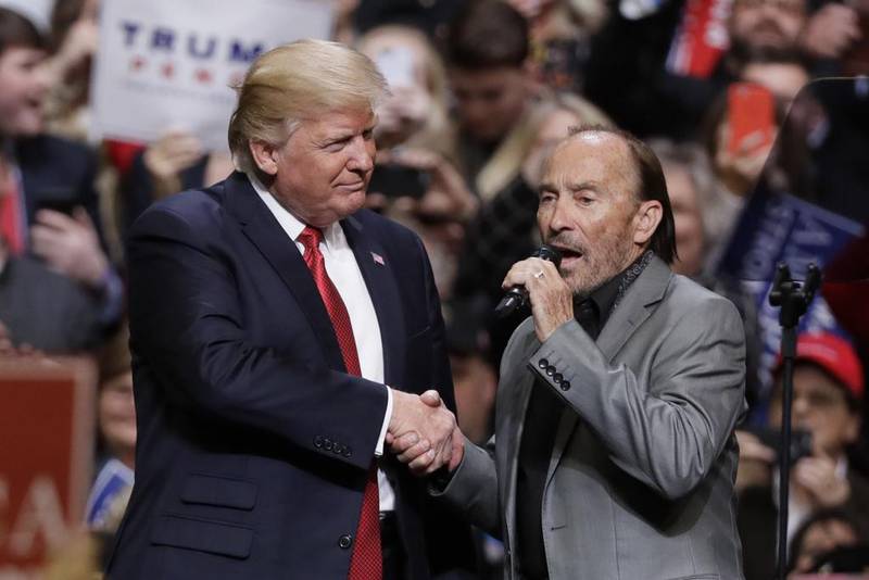 US president Donald Trump shakes hands with country music singer Lee Greenwood as he sings 'God Bless the USA' at a rally in Nashville on March 15, 2017. Mark Humphrey / AP Photo