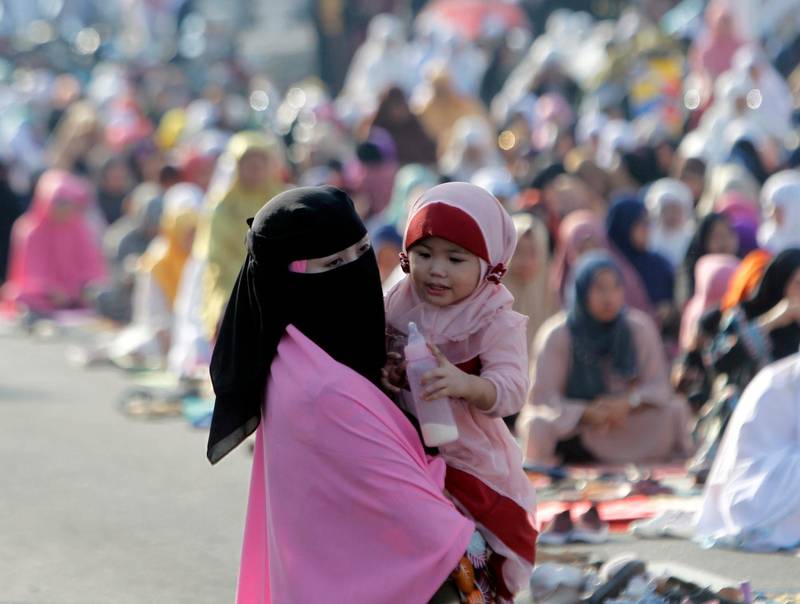 A Filipino mother carries a baby as she attends an Eid Al Adha prayer service in Zamboanga city, southern Philippines.  EPA