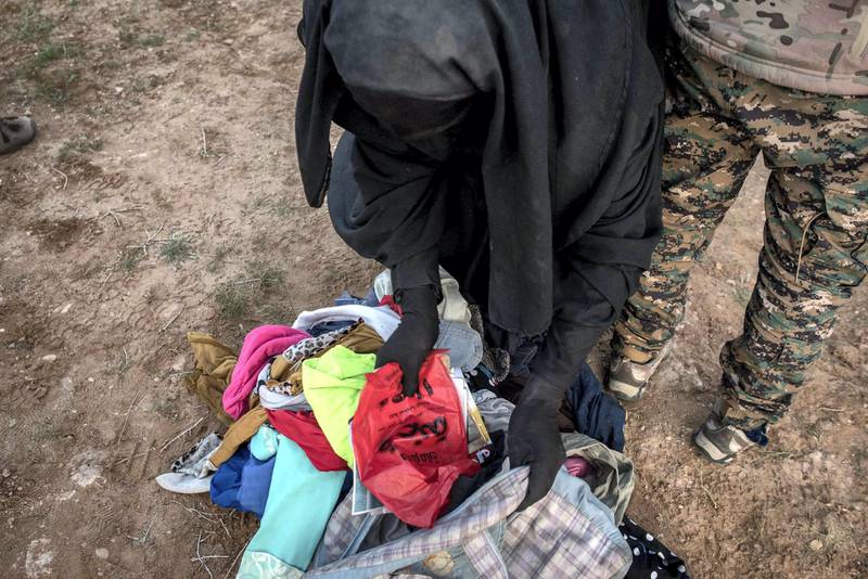 A woman empties her baggage while being searched by Syrian Democratic Forces after fleeing from the last pocket of ISIS territory in Syria, outside Baghouz, 28 February 2019. Campbell MacDiarmid