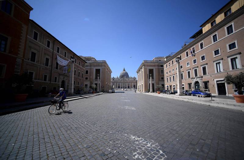 A woman wearing a face mask cycles in the empty   Via della Conciliazione, as the Vatican's Saint Peter's Basilica is seen in the background, in Rome.  AFP