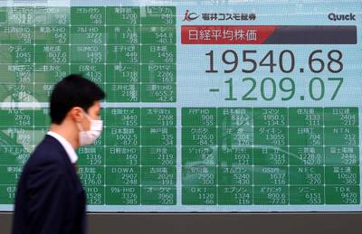 A passerby wearing a protective face mask following an outbreak of the coronavirus, walks past an electronic display showing Asian markets indices outside a brokerage in Tokyo, Japan. Reuters