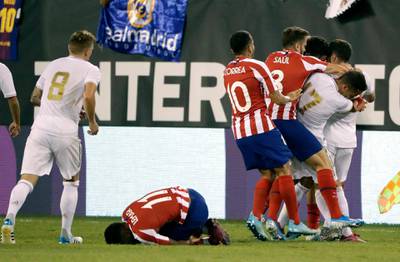 Atletico Madrid's Thomas Lemar reacts after being injured as teammates fight with Real Madrid players. AP Photo