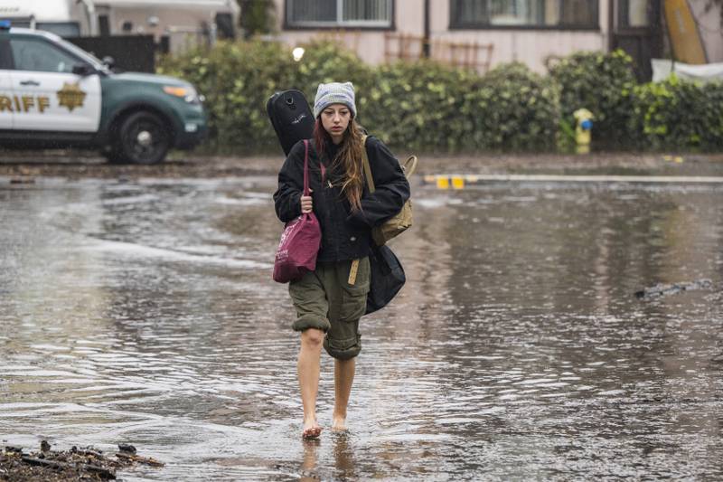 Naia Skogerson leaves her house as floodwaters rise in the Rio Del Mar neighbourhood of Aptos. AP