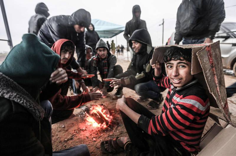 Palestinian youths and protesters sit together around a fire as they seek shelter from the rain, during a demonstration near the border with Israel east of Gaza city. AFP
