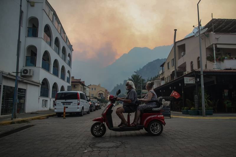 People use a scooter in Turunc before the village is evacuated.