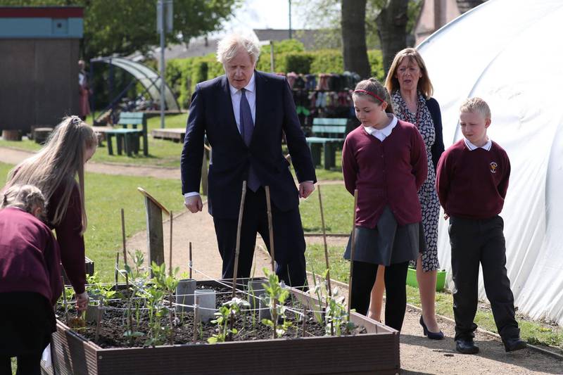 Boris Johnson is shown the vegetable garden at Cleves Cross Primary school. AFP
