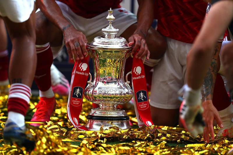The FA Cup sits in the pitch surrounded by Arsenal players. Getty