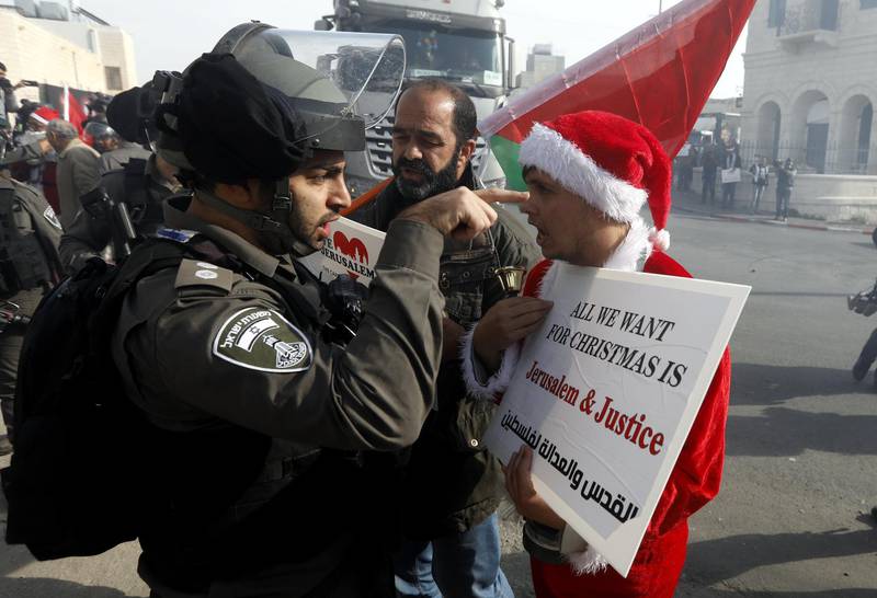 epa06403941 Israeli soldier argues with a Palestinian protester dressed as Santa Claus during a demonstration in the West Bank city of Bethlehem, 23 December 2017.  EPA/ABED AL HASHLAMOUN