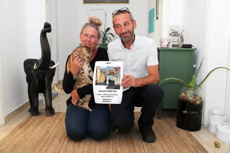 Jacqueline Appleby and her husband Dave with their cats at their villa in Abu Dhabi. Dave is showing the poster of their lost cats. Pawan Singh / The National