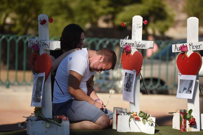 TOPSHOT - Ethan Avanzino grieves beside a white cross for his friend Cameron Robinson, one of 58 victims of Sunday night's mass shooting, on the Las Vegas Strip just south of the Mandalay Bay hotel, October 6, 2017 in Las Vegas, Nevada.
On October 1, 2017 Stephen Paddock killed at least 58 people and injured more than 450 after he opened fire on a large crowd at the Route 91 Harvest country music festival. The massacre is one of the deadliest mass shooting events in US history. / AFP PHOTO / Robyn Beck