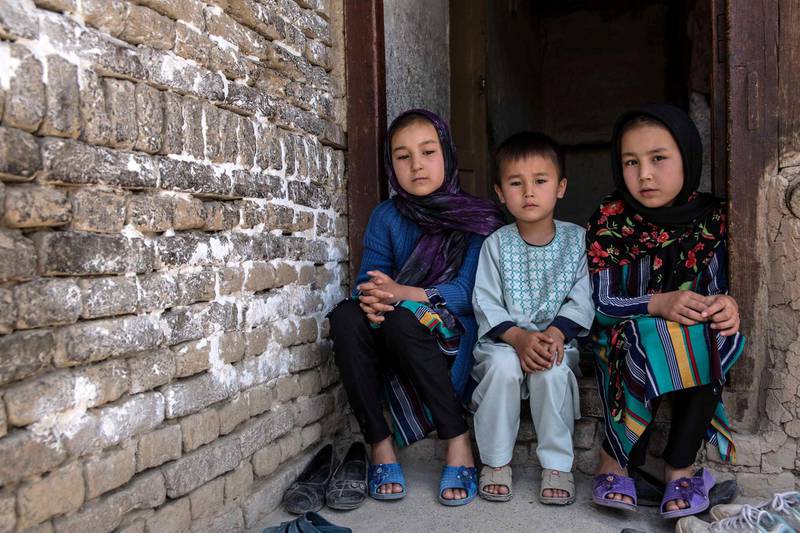 Mr Gul's family sits in their living room, a photo of the children's mother on top of the shelf. She was killed in the attack on a Kabul aternity ward that hasn't been claimed by any militant group. Stefanie Glinski for The National