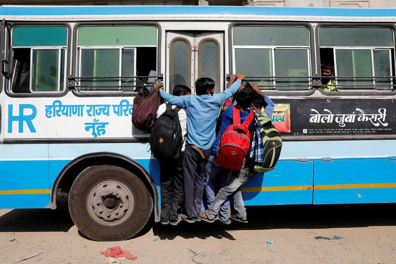 Migrant workers hang on to a door of their moving bus as they return to their villages, during a 21-day nationwide lockdown to limit the spreading of coronavirus disease (COVID-19), in Ghaziabad, on the outskirts of New Delhi. REUTERS