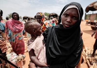 A Sudanese woman carries her daughter after being relocated from makeshift shelters to a refugee camp in Ourang, Chad.